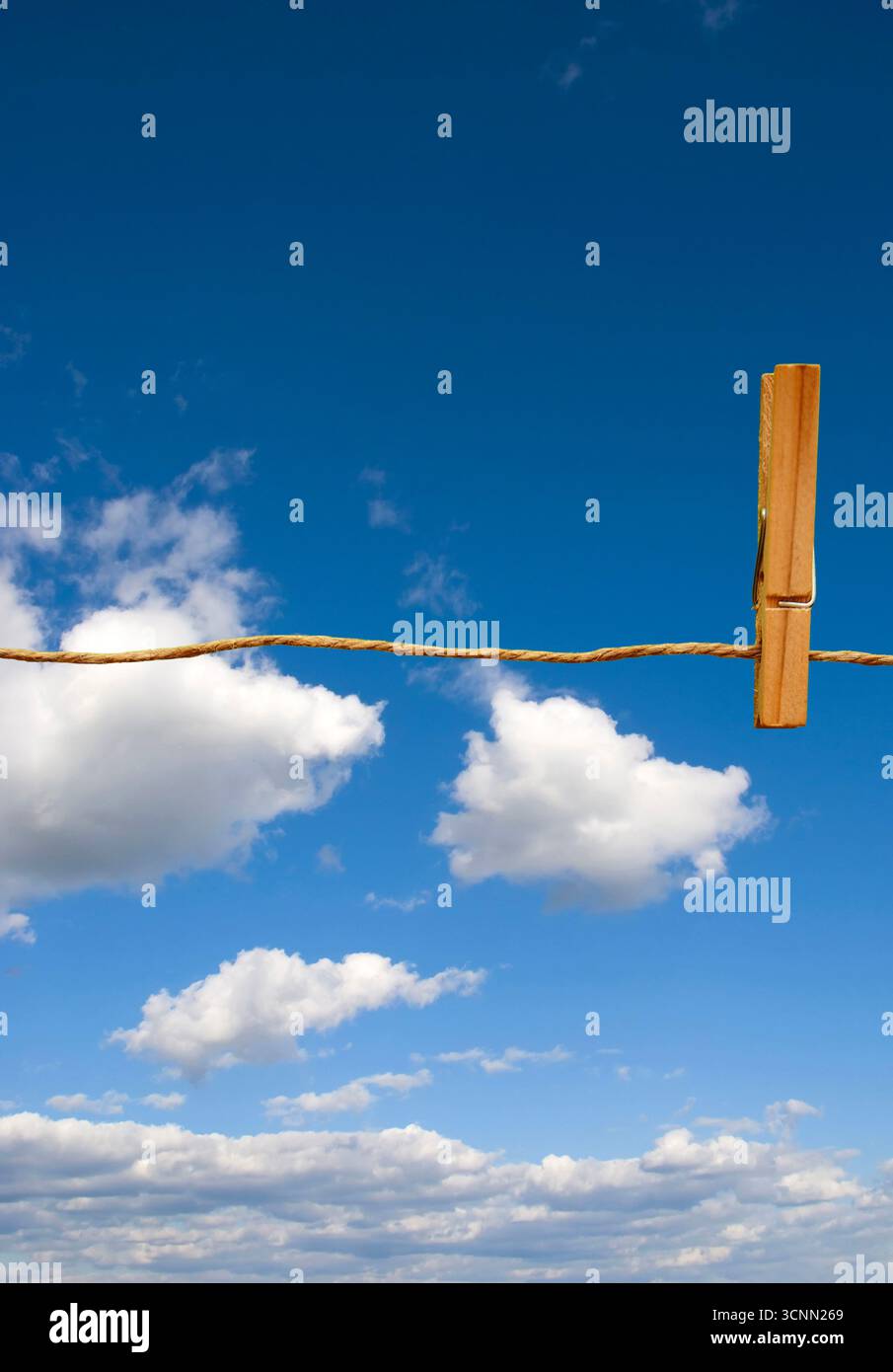 Hölzerne Kleiderschachtel, die an einem Seil befestigt ist, mit wolkenblauem Hintergrund, der Einfachheit, Wäsche und Alltag im Freien symbolisiert Stockfoto
