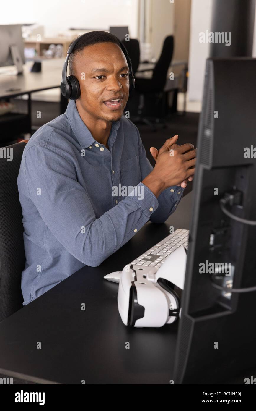 afroamerikanischer männlicher Büroangestellter, der beim Treffen mit dem vr-Headset auf dem Bildschirm Gesten macht Stockfoto