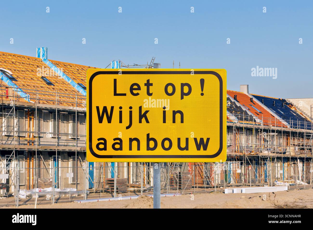 Unterschreiben Sie mit dem niederländischen Text für 'Achtung - Wohngebiet im Bau' vor neuen Familienhäusern in den Niederlanden Stockfoto