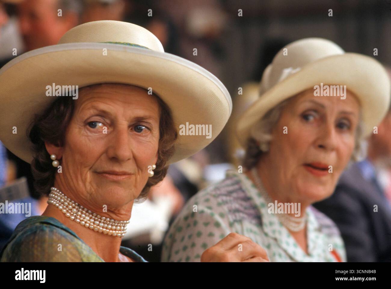 Choker-Halskette Mit Perlen. Ältere Frau mit Perlenhalskette und Perlenohrringen und einem großen Sommerhut aus Stroh. Modisch unter „Oberklasse“-Frauen eines bestimmten Alters, eine Mode-Statment in den 1980er Jahren Großbritannien. Sie schauen sich die Country Show an. Peterborough, England 1985. Stockfoto