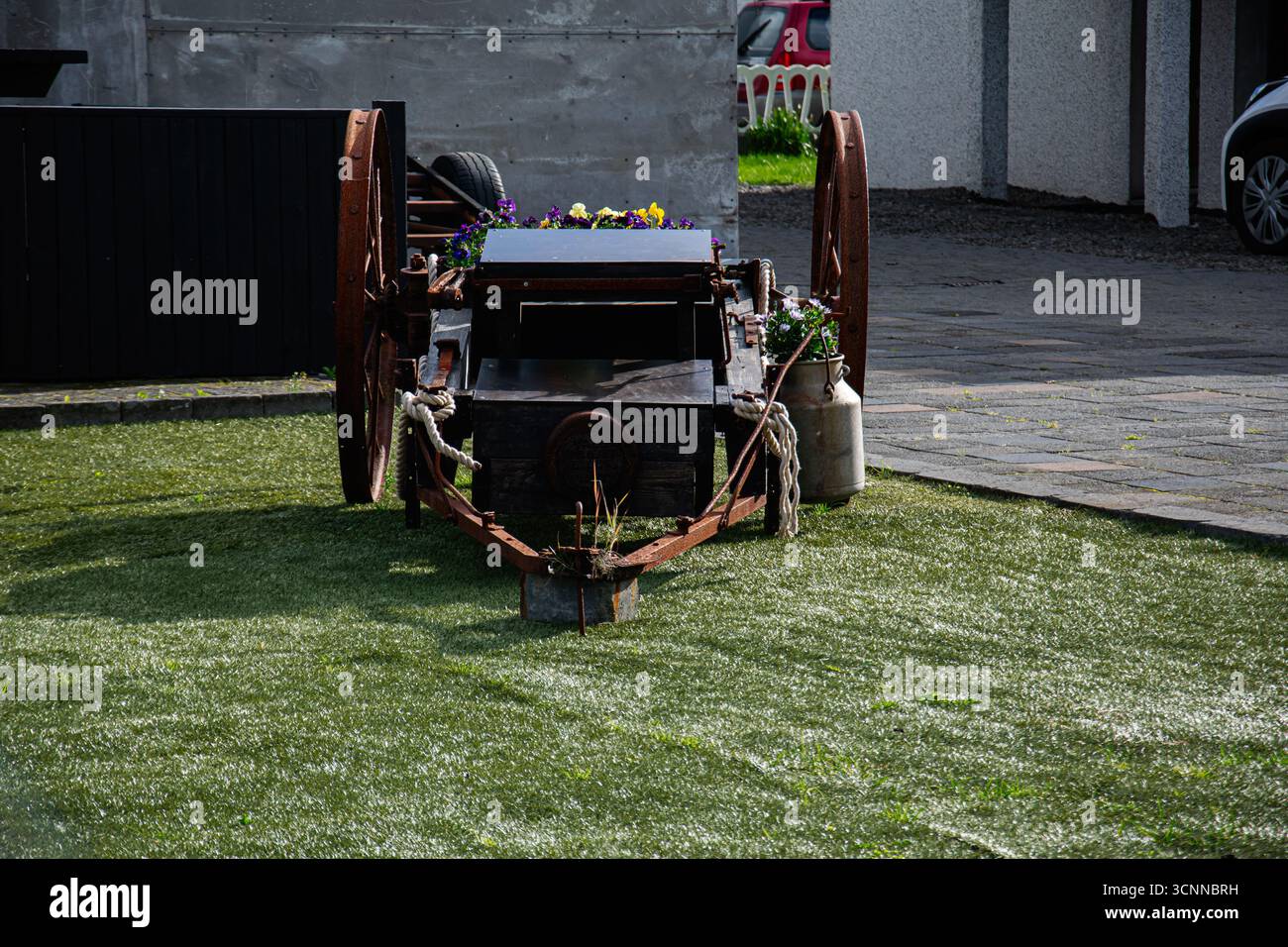 Akranes, Island - 17. September 2025: Ein verwitterter Holzwagen mit Blumen und Seil auf einem grünen Rasen in Island Akranes. Stockfoto