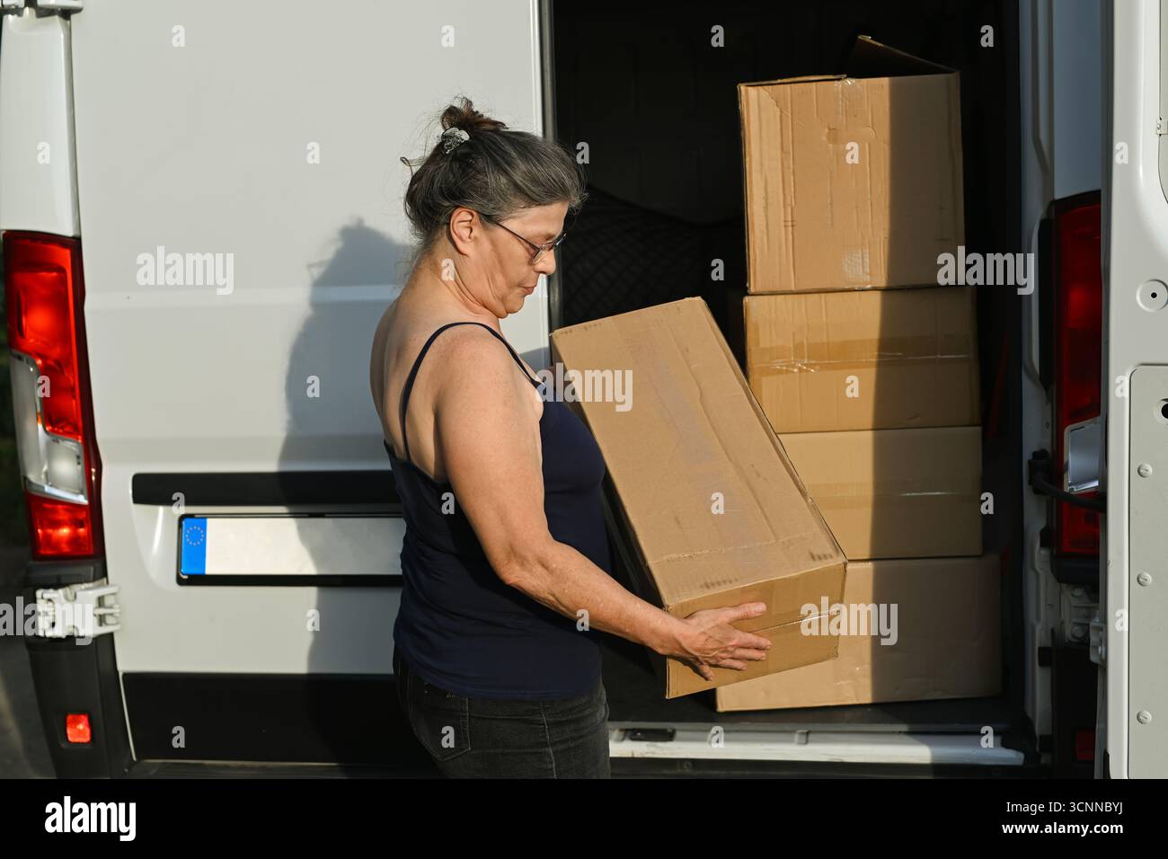 Eine Frau nimmt ein Paket aus dem Van. Stockfoto