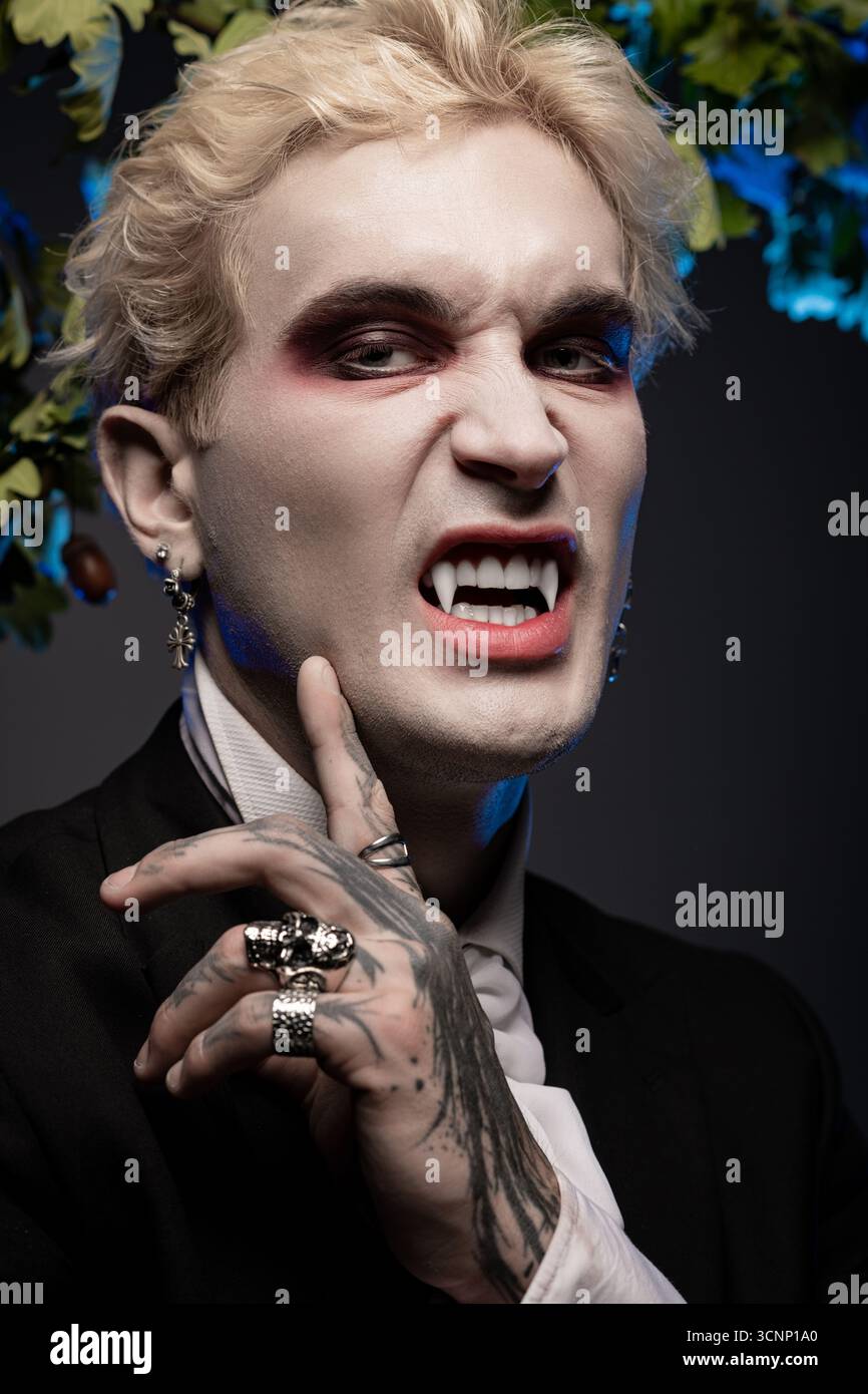 Ein junger Mann zeigt ein fesselndes Halloween-Kostüm mit auffälligem Make-up und auffälligen Accessoires. Stockfoto
