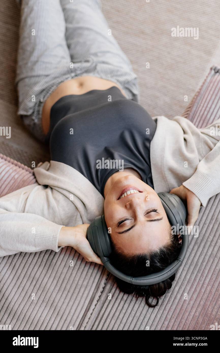 Frau, die sich zu Hause entspannt, Musik nach der Arbeit genießt. Stockfoto