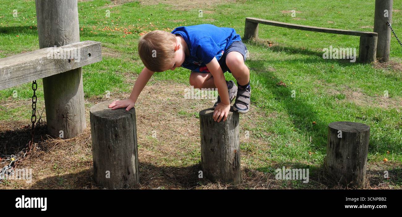 Kleiner Junge, der auf Baumstümpfen im Spielpark spielt. Stockfoto Kleiner Junge, der auf Baumstümpfen im Spielpark spielt. Stockfoto
