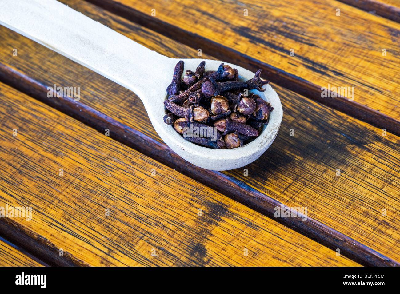 Ein hölzerner Teelöffel voller Zehen auf einer hölzernen Tischplatte Stockfoto