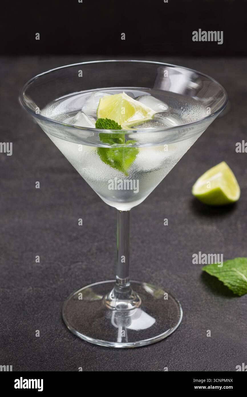 Nebeliges Weinglas mit Limette, Minze und Eis. Schwarzer Hintergrund. Draufsicht Stockfoto