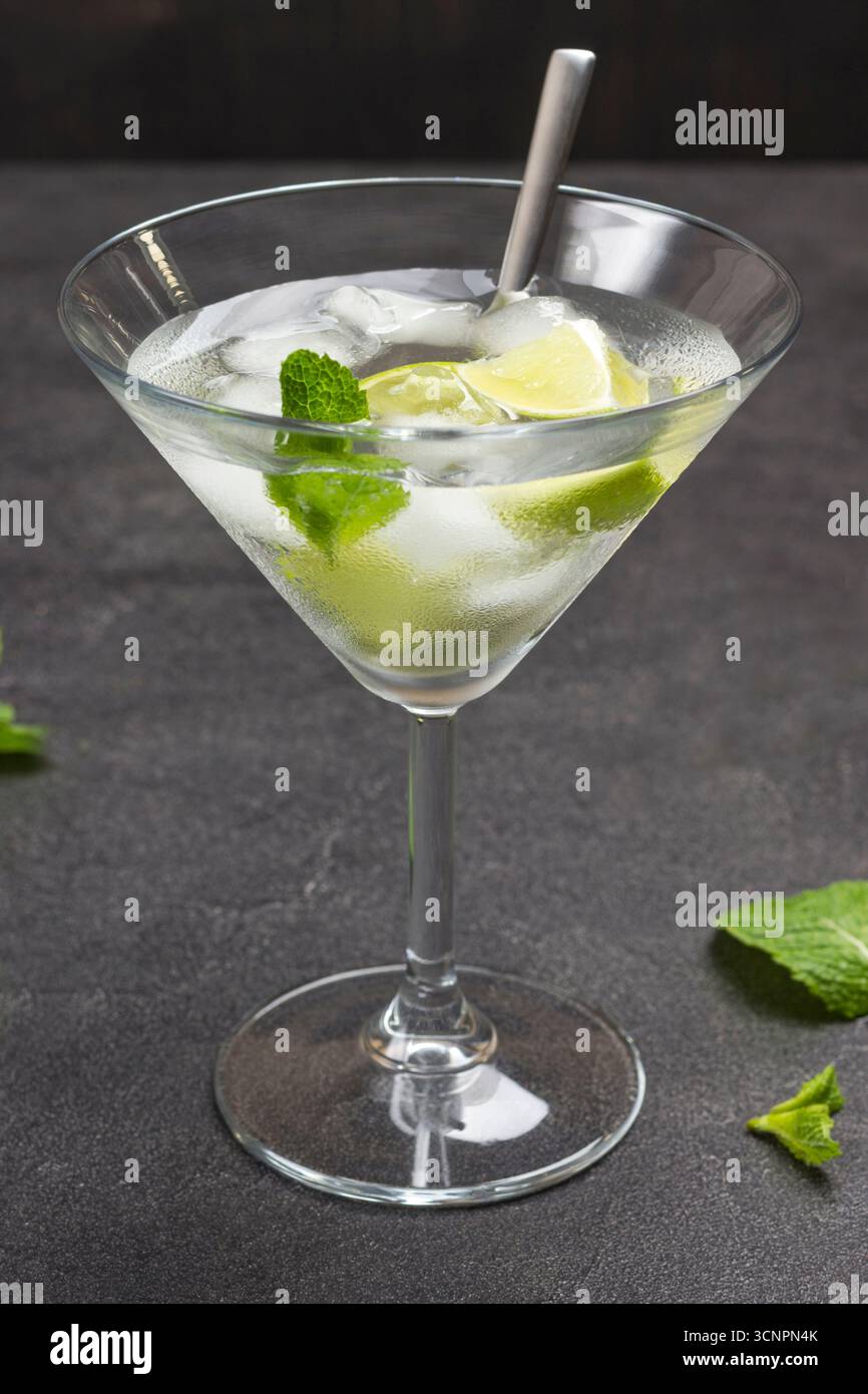 Nebeliges Weinglas mit Limette und Eis. Minzzweige auf dem Tisch. Schwarzer Hintergrund. Draufsicht Stockfoto