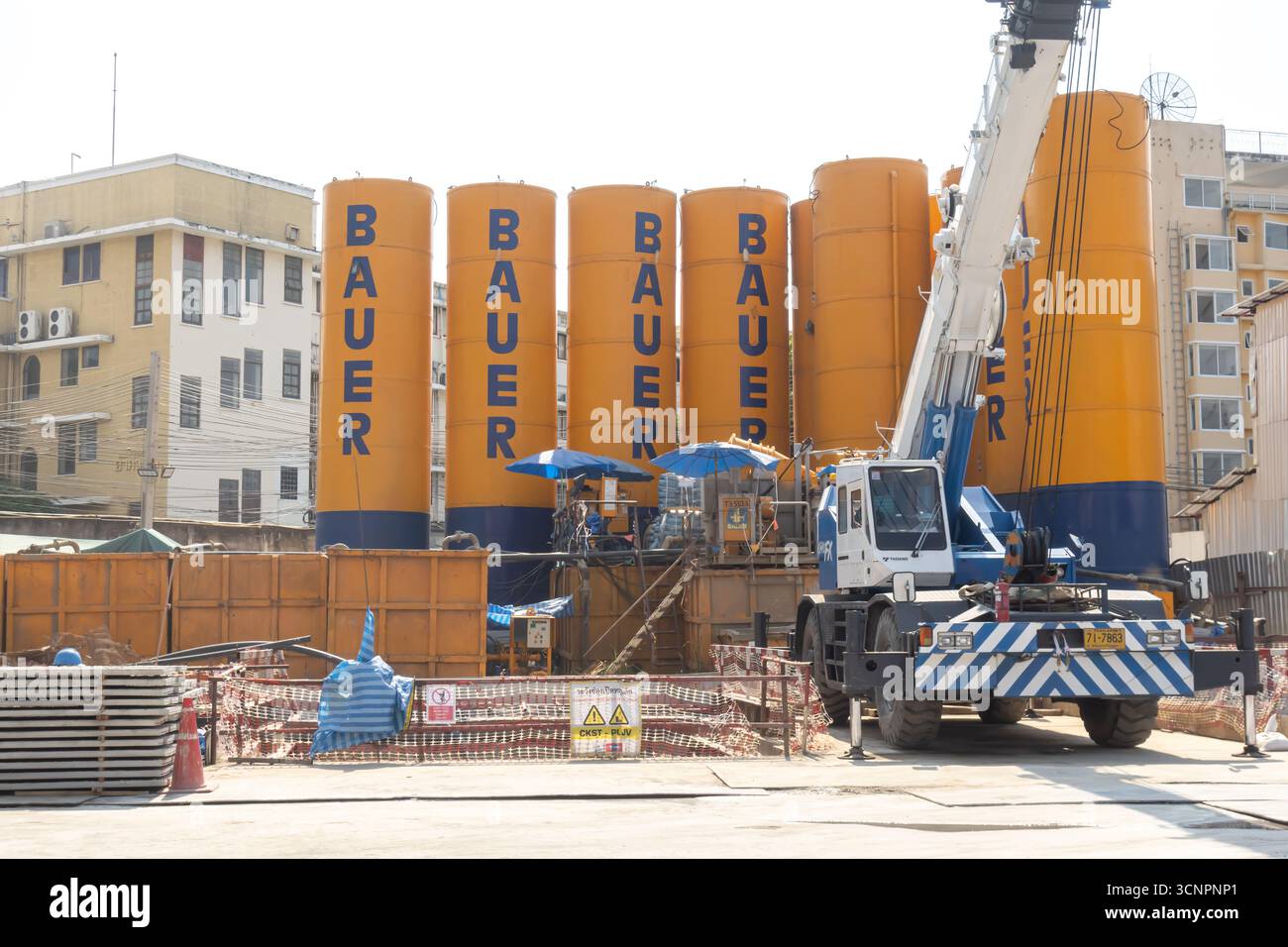 Eine Baustelle mit mehreren großen gelben und blauen Bauer-Silos und einem Kran. Bangkok, Thailand Stockfoto