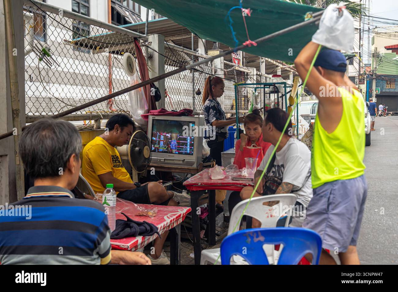 Familie und Freunde sehen Muay Thai Kämpfe im fernsehen im urbanen Außenbereich von Bangkok, Phra Nakhon Stockfoto