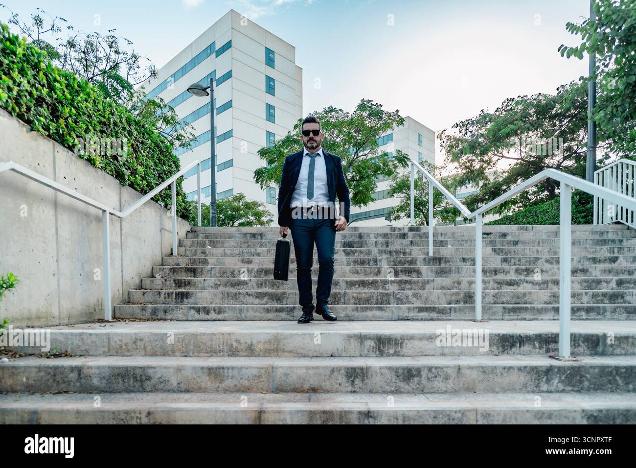 Professioneller Geschäftsmann mit Aktenkoffer, der die Stadtreppen vor Bürogebäuden hinuntergeht Stockfoto