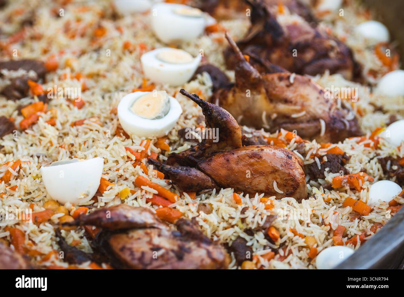 Traditionelles tadschikisches Reisgericht mit gebratenen Wachteln, Karotten und gekochten Eiern. Nahaufnahme eines festlichen Plovs, ein typisches Gericht der tadschikischen Küche Stockfoto