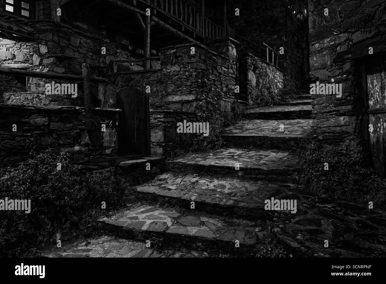 Mystisches Steindorf bei Nacht mit alten Treppen und rustikalen Häusern in Portugal, beleuchtet in stimmungsvollem Licht Stockfoto