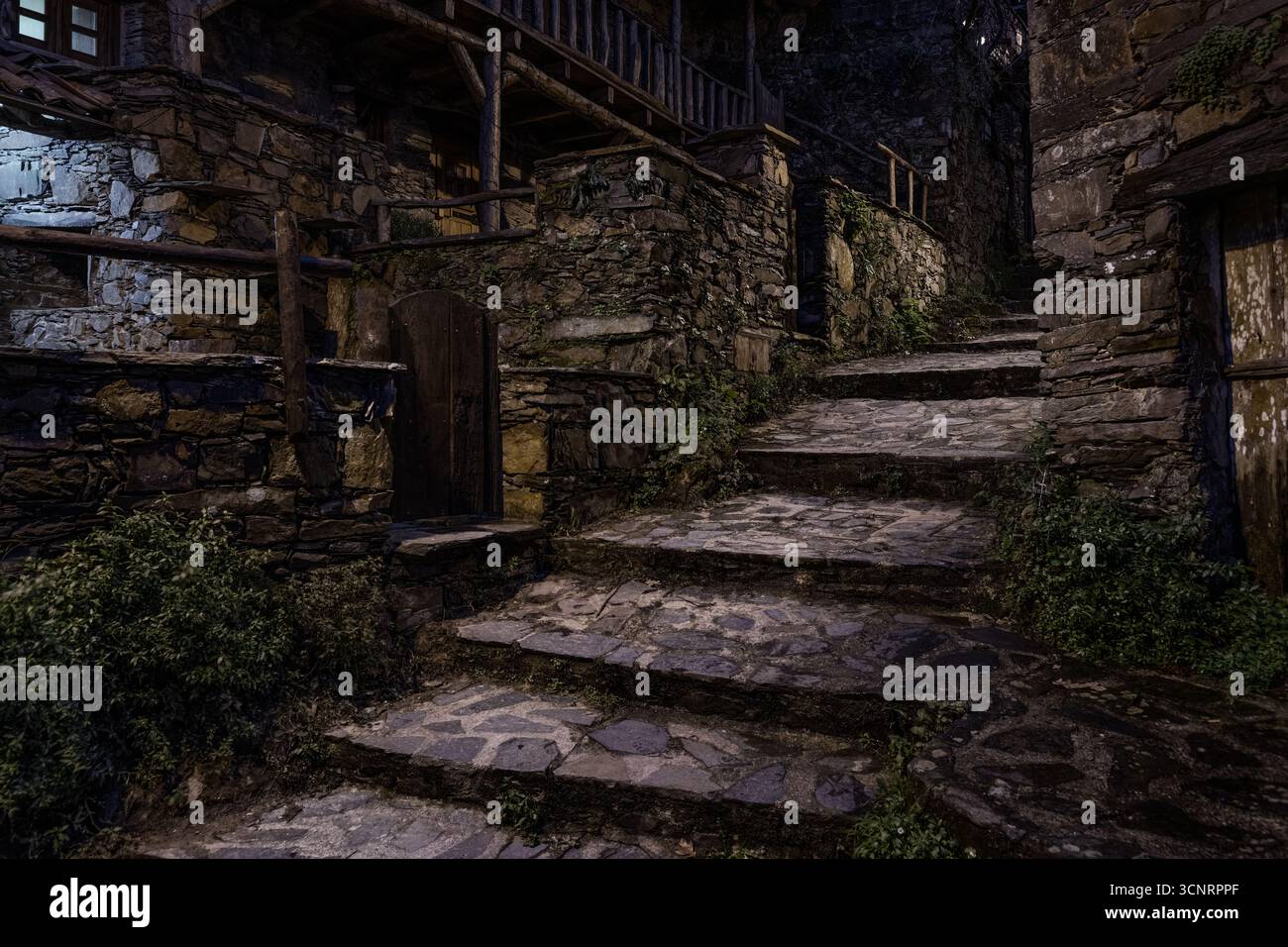 Mystisches Steindorf bei Nacht mit alten Treppen und rustikalen Häusern in Portugal, beleuchtet in stimmungsvollem Licht Stockfoto