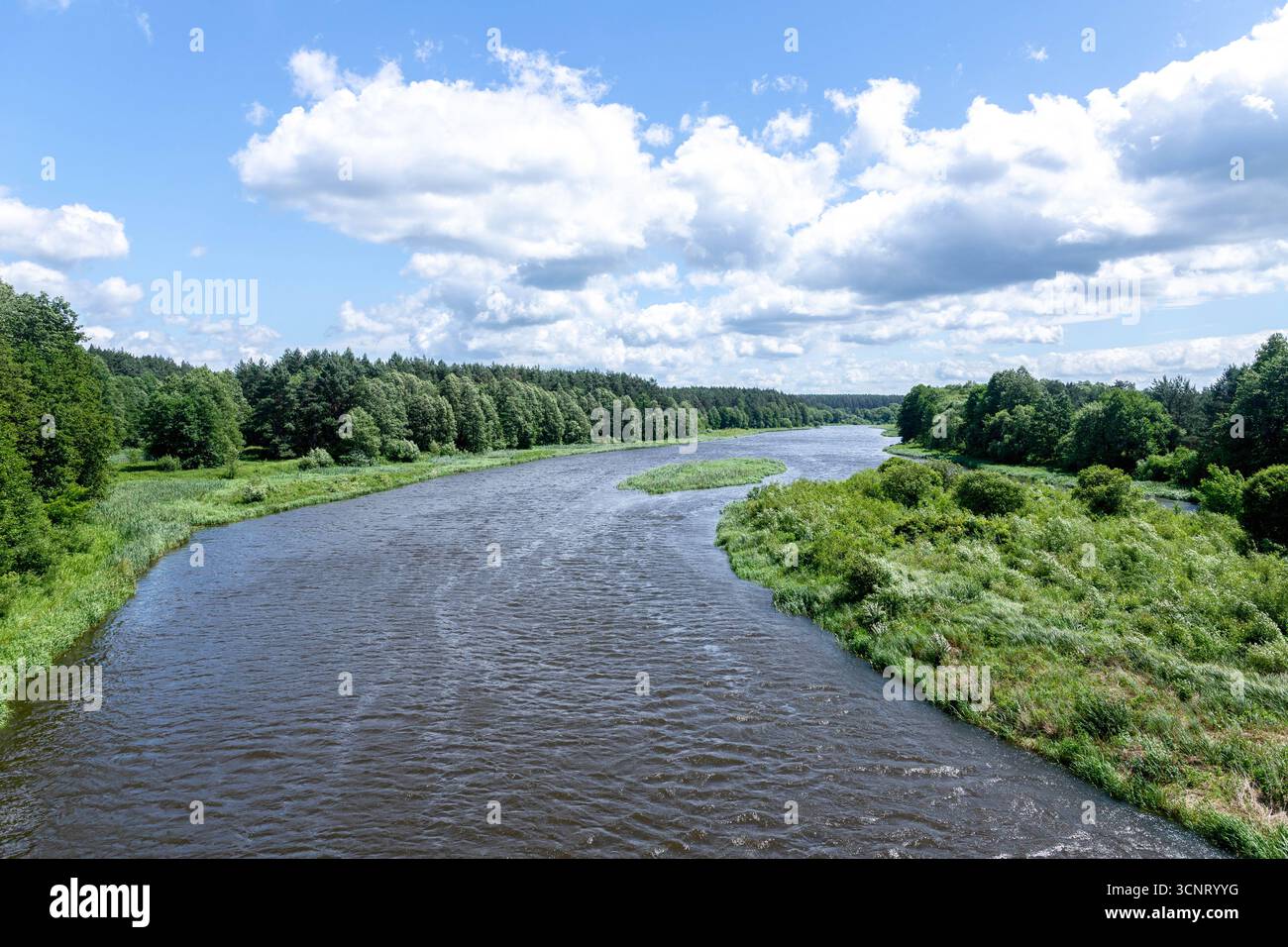 Ein malerischer Fluss fließt sanft und reflektiert das dichte Grün an seinen Ufern. Die Gegend ist ruhig, mit üppigem Gras und Bäumen rund um das Wasser Stockfoto