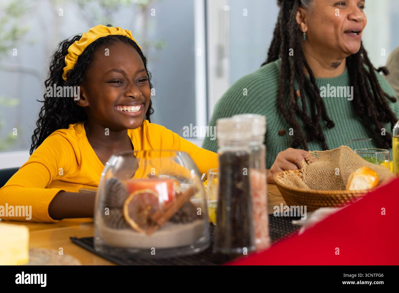 Afroamerikanische Mutter und Tochter sitzen am Esstisch, greifen Brotkorb, Kopierraum Stockfoto