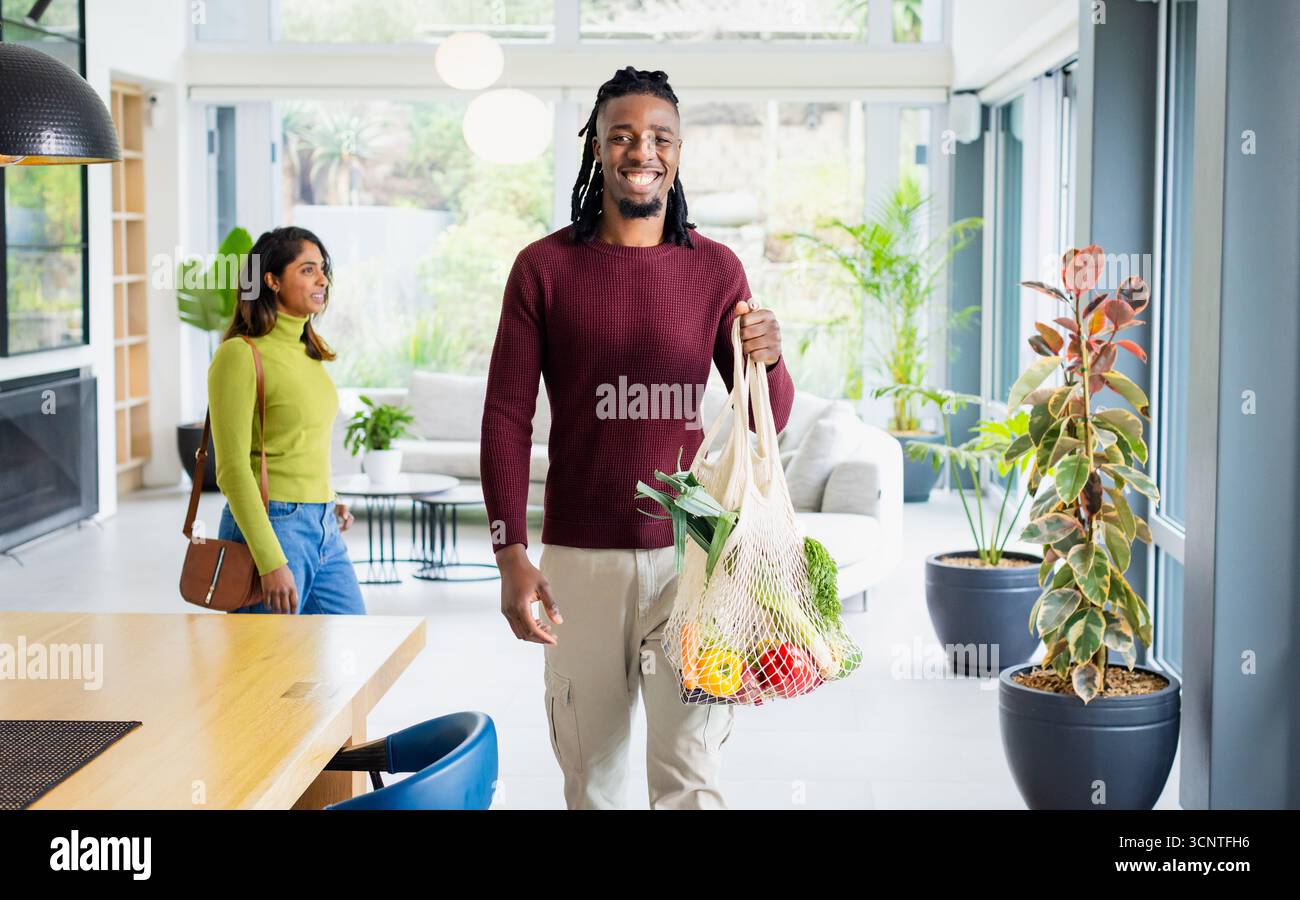 Diverse Paare betreten den modernen Wohnbereich mit Mesh-Einkaufstasche und Leder-Schultertasche Stockfoto