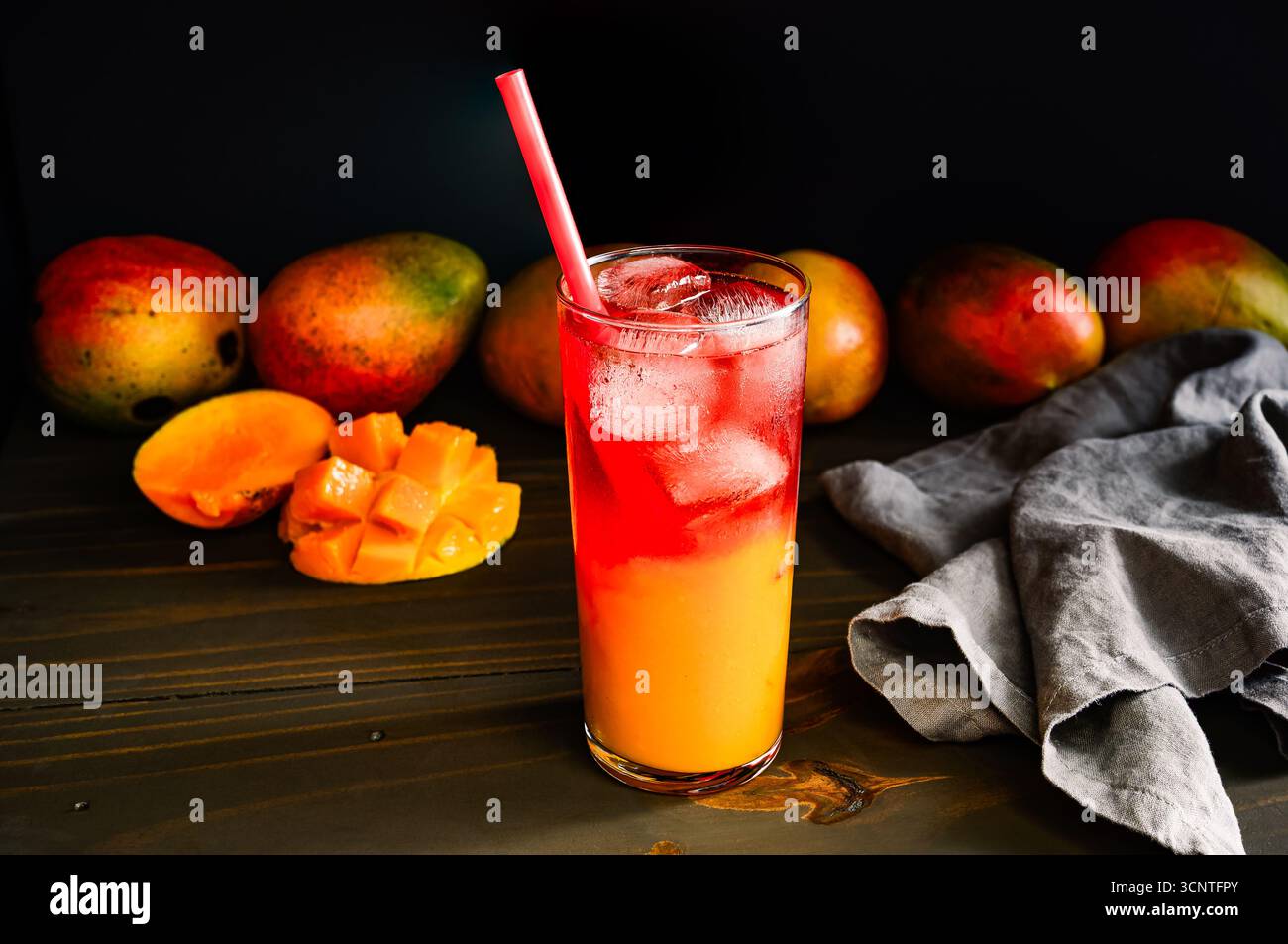 Hibiskus-Eistroh in großem Glas mit Strohhalm: Obst- und Kräutertee serviert auf Eis in einem Tumbler mit Strohhalm und frischen Mangos Stockfoto