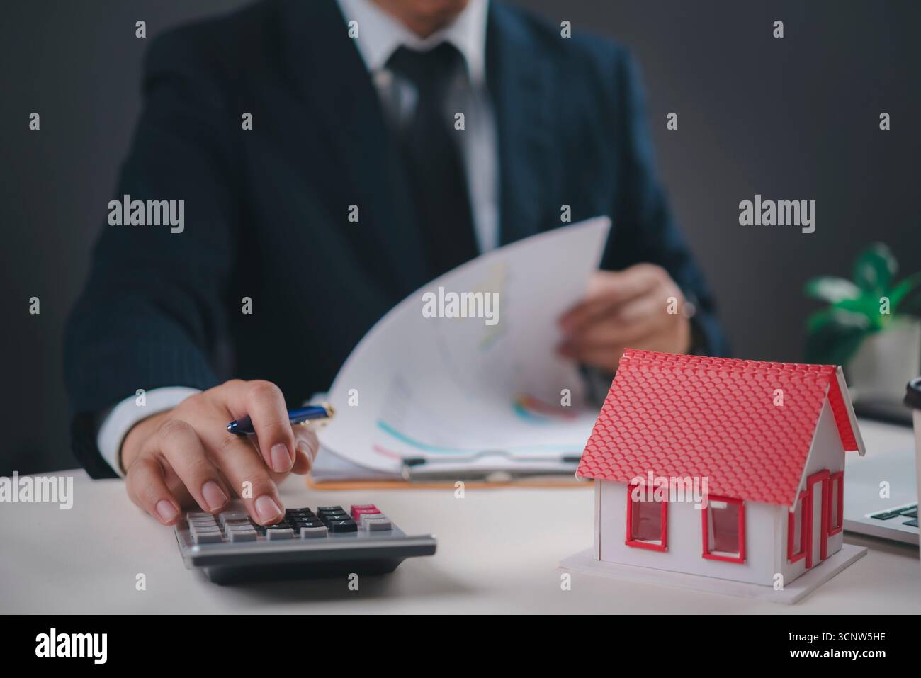 Geschäftsmann berechnet Hypothekenzahlungen, überprüft Finanzdokumente für Immobilieninvestitionen. Zeigt Immobilienfinanzierung, Wohnungskreditplanung, A Stockfoto