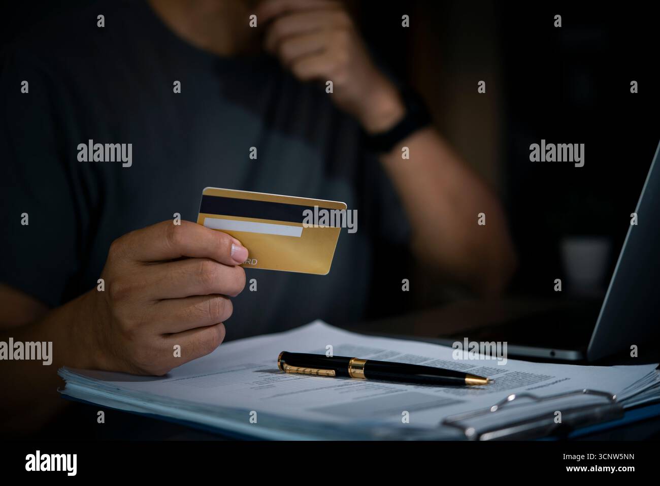 Der Mann hält eine Online-Zahlung mit Kreditkarte oder eine Finanztransaktion mit einem Laptop und Dokumenten auf dem Schreibtisch. Digitale Finanzen, sicherer E-Commerce und Busine Stockfoto