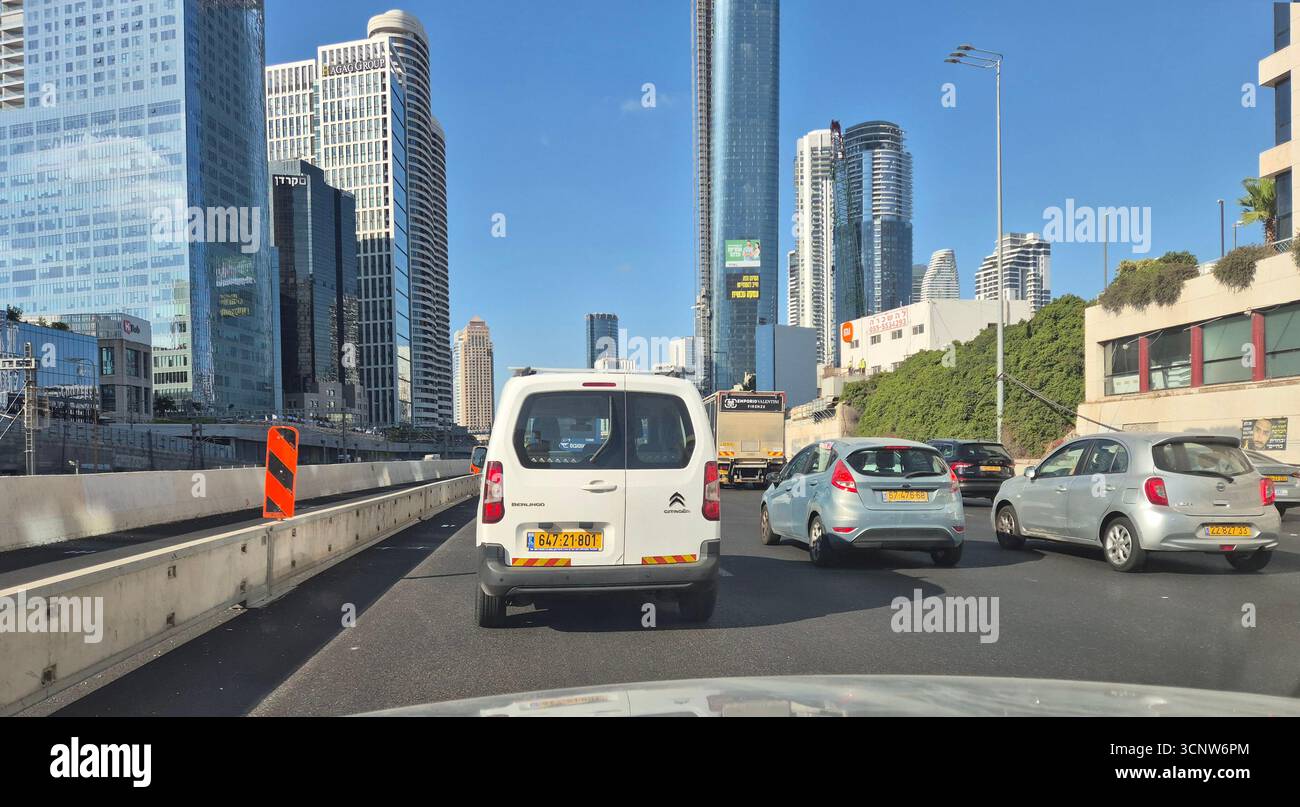 Tel Aviv, Israel - 6. August 2025: Zwischen hohen Wolkenkratzern fließt unter klarem blauem Himmel der Verkehr Stockfoto