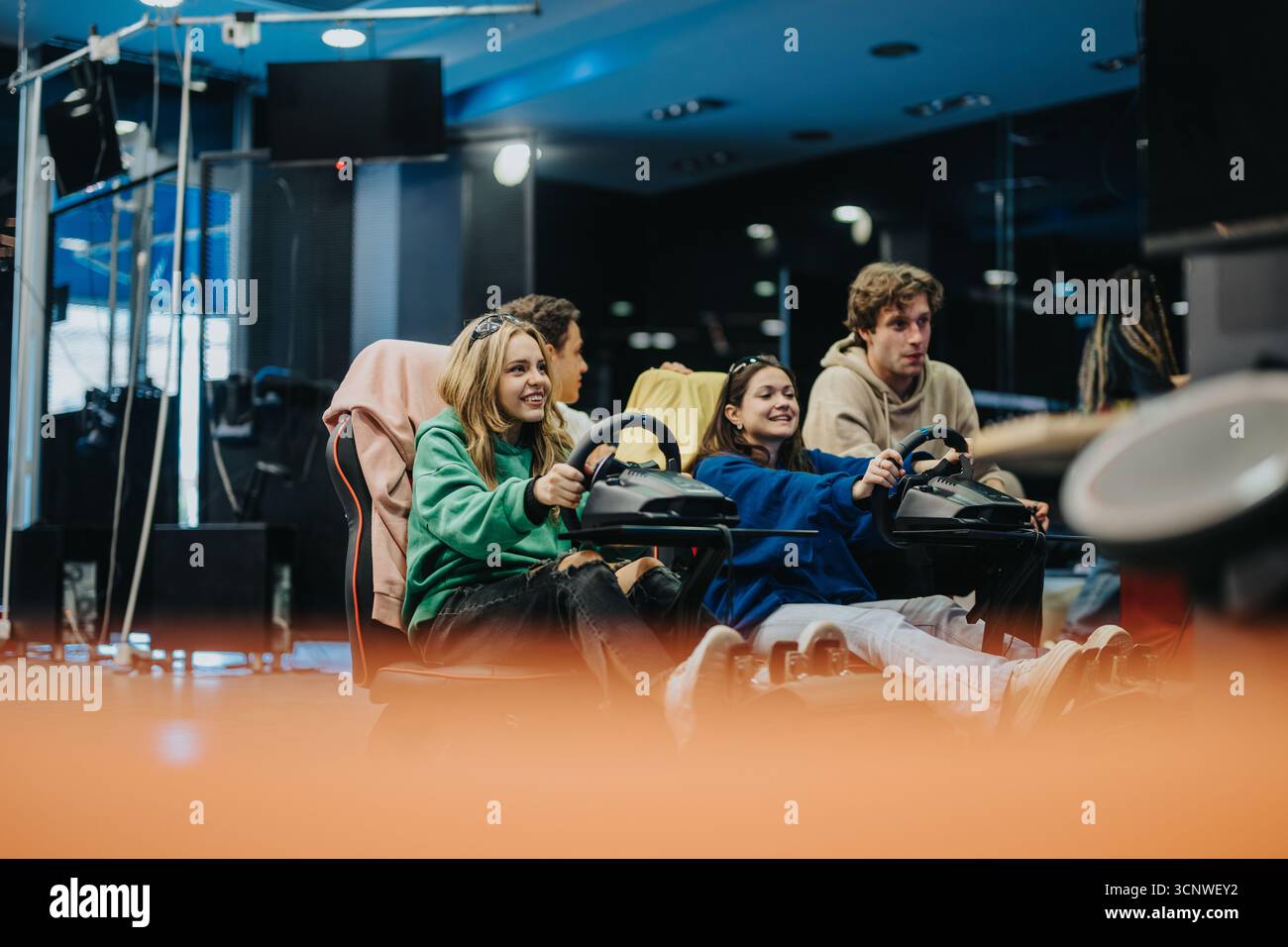 Gruppe von Freunden, die das Rennspiel-Simulationserlebnis in einer Arcade genießen Stockfoto