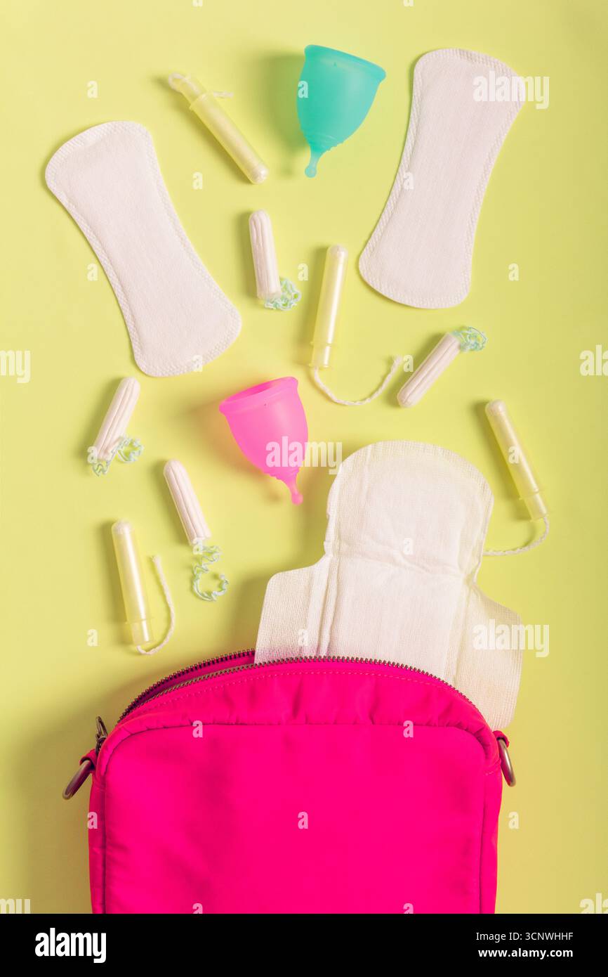 Ansicht von oben auf verschiedene Menstruationsprodukte, einschließlich Hygienepads, Tampons und Menstruationstassen auf einem lebendigen Hintergrund. Maßnahmen zur Förderung der Nachhaltigkeit Stockfoto