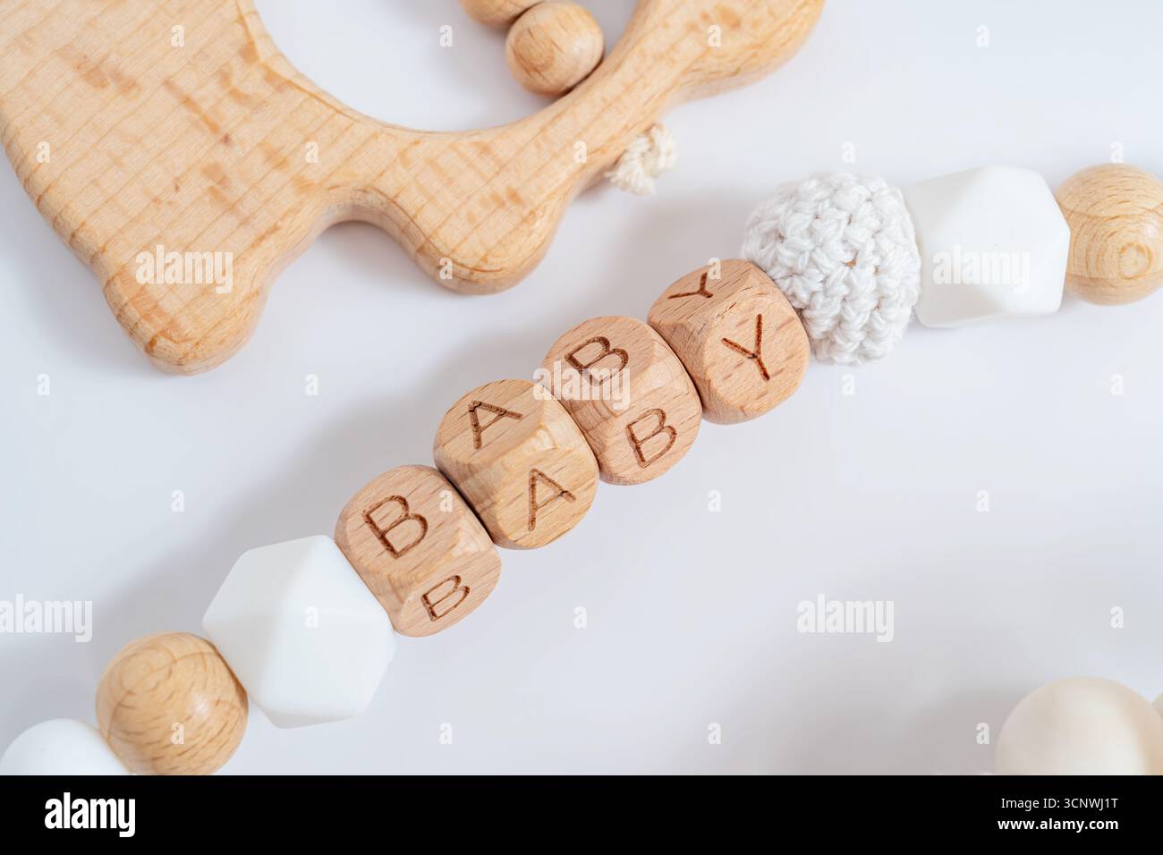 Eine bezaubernde Kollektion von Babyaccessoires mit Holzblöcken, die BABY buchstabieren, und einem handgefertigten Holzbeißring, ideal für ein einzigartiges und du Stockfoto