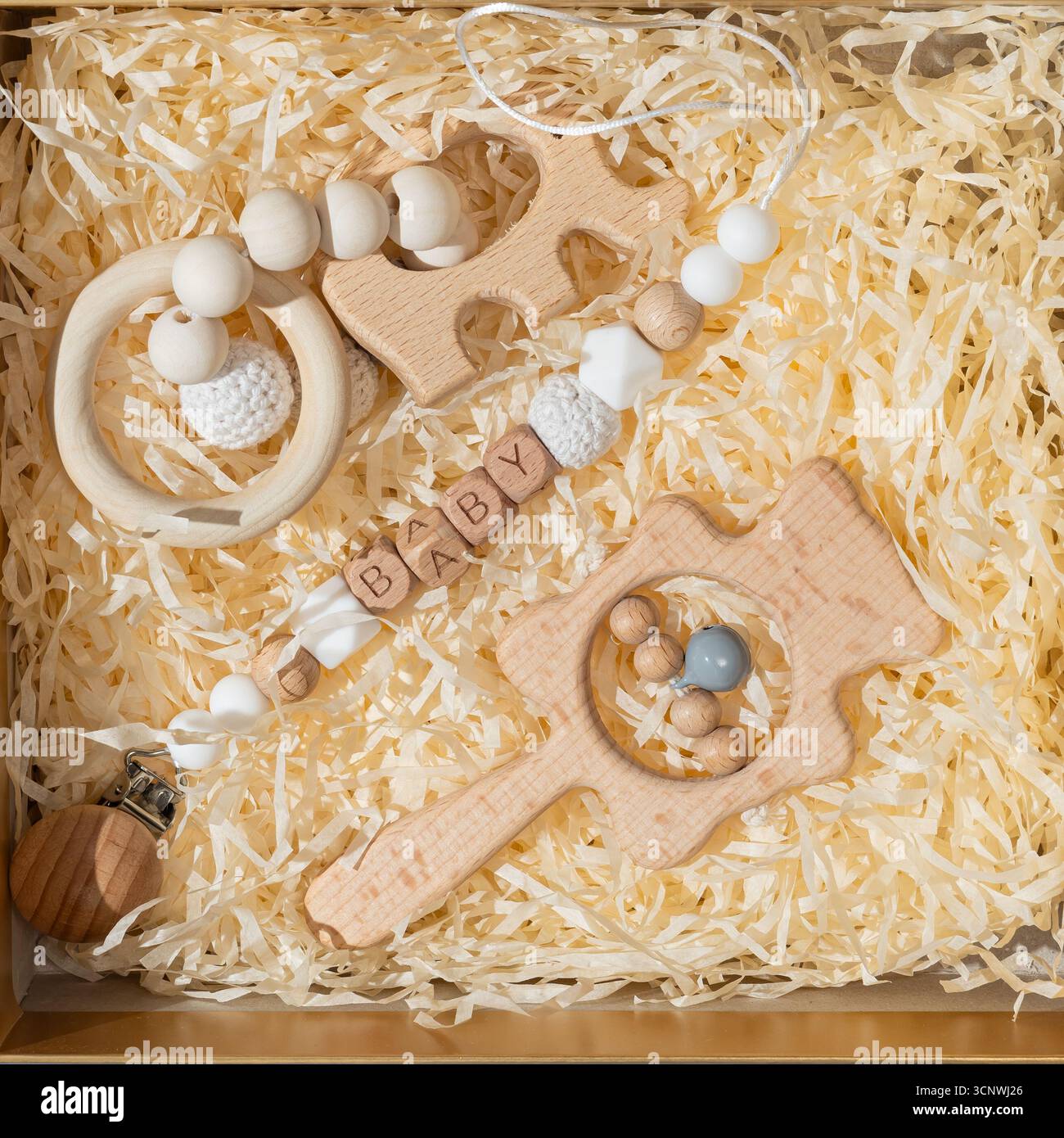 Eine bezaubernde Kollektion von Babyspielzeugen aus Holz, eingebettet in ein weiches Bett aus geschreddertem Papier, perfekt für die sensorische Entwicklung von Kleinkindern und als einzigartiges Geschenk für Neues Stockfoto