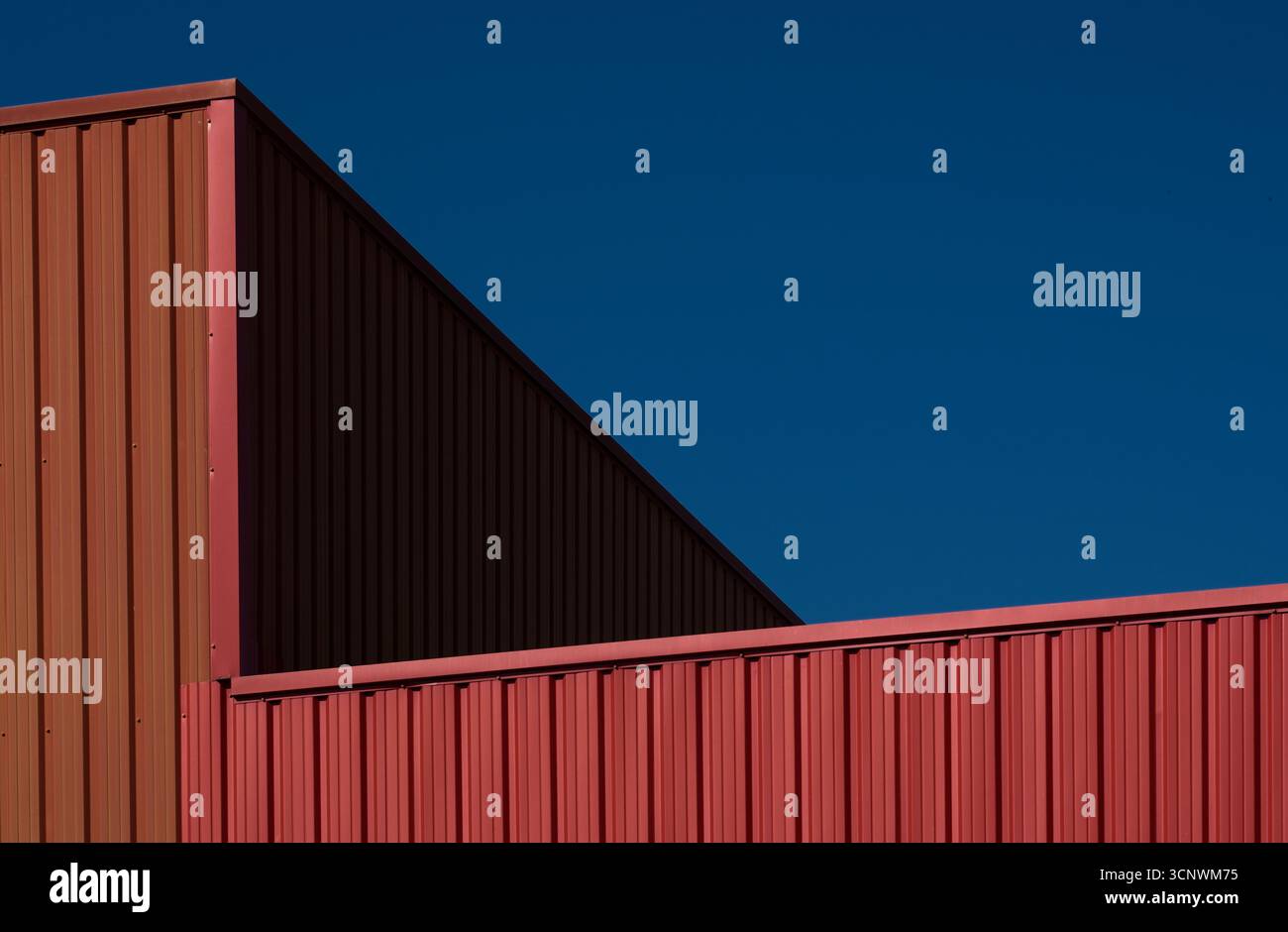 Eine beeindruckende Komposition moderner Architektur mit markanten geometrischen Linien und einem leuchtend blauen Himmel. Das Bild hebt das Zusammenspiel von Co hervor Stockfoto