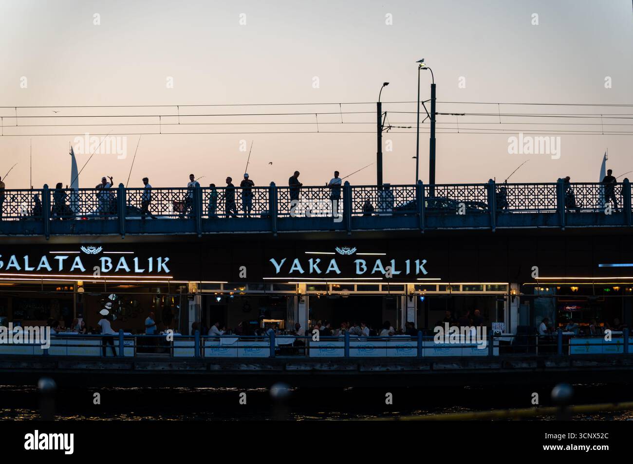 Männer fischen bei Sonnenuntergang auf der Galata-Brücke, Istanbul, Turkiye Stockfoto