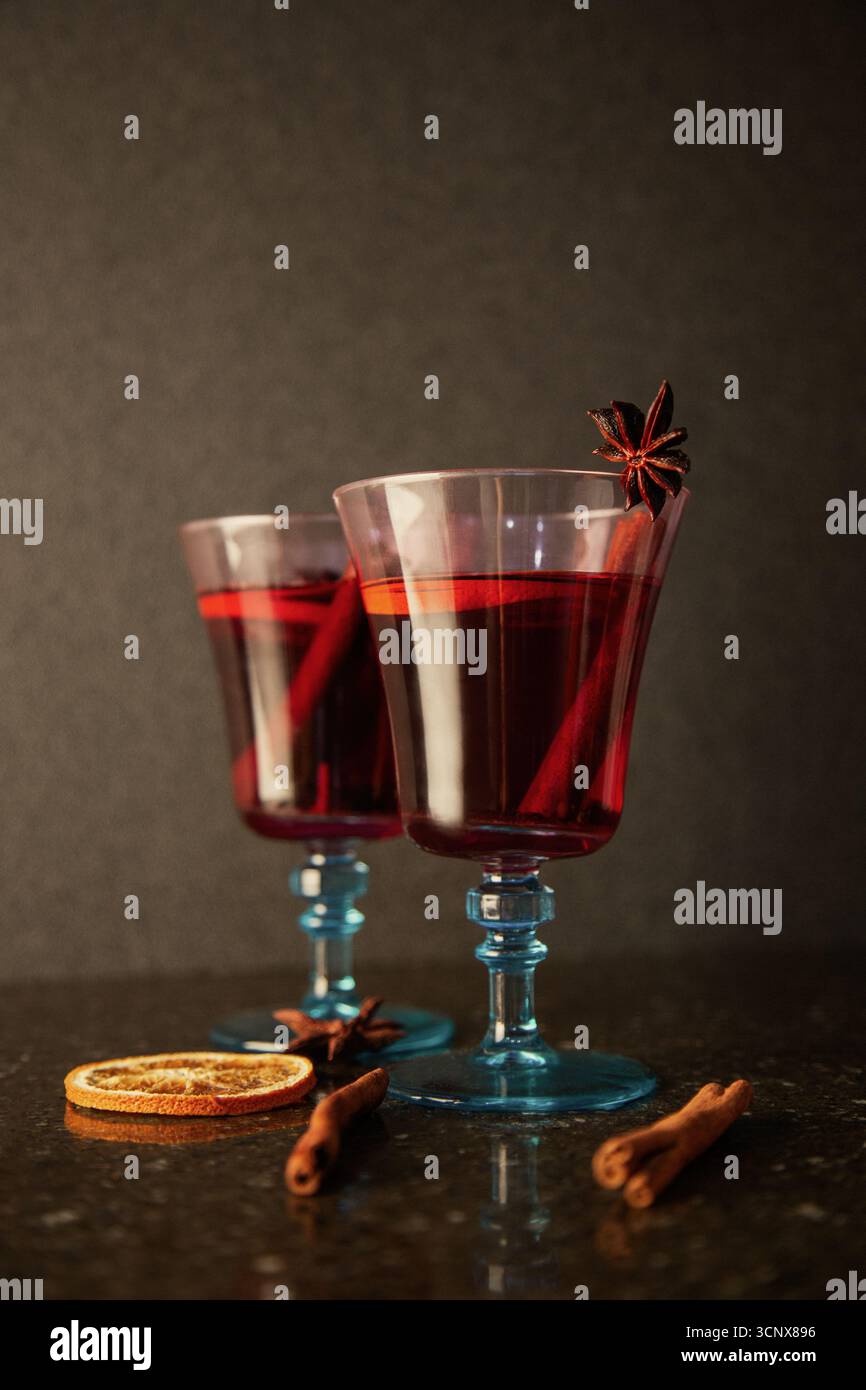 Elegante Gläser Glühwein, garniert mit Sternanis, gepaart mit Zimtstangen und getrockneten Orangenscheiben. Ein warmes, festliches Getränk, perfekt für Chris Stockfoto