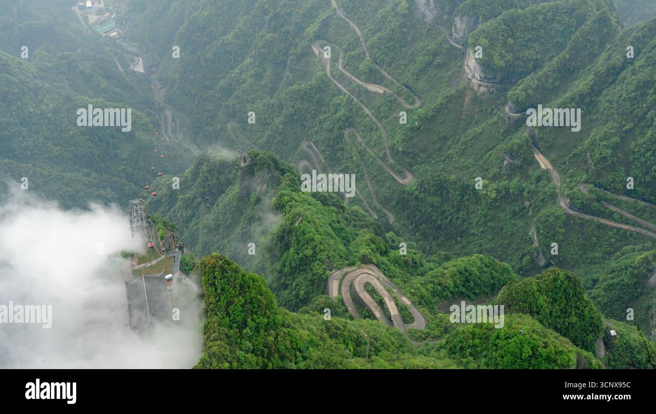 Nebeliger Blick aus der Vogelperspektive auf die 99-Bend Avenue to Heaven Road und eine Seilbahn auf dem Berg Tianmen in Zhangjiajie, China. Diese Höhenzone, Tianmen Don Stockfoto