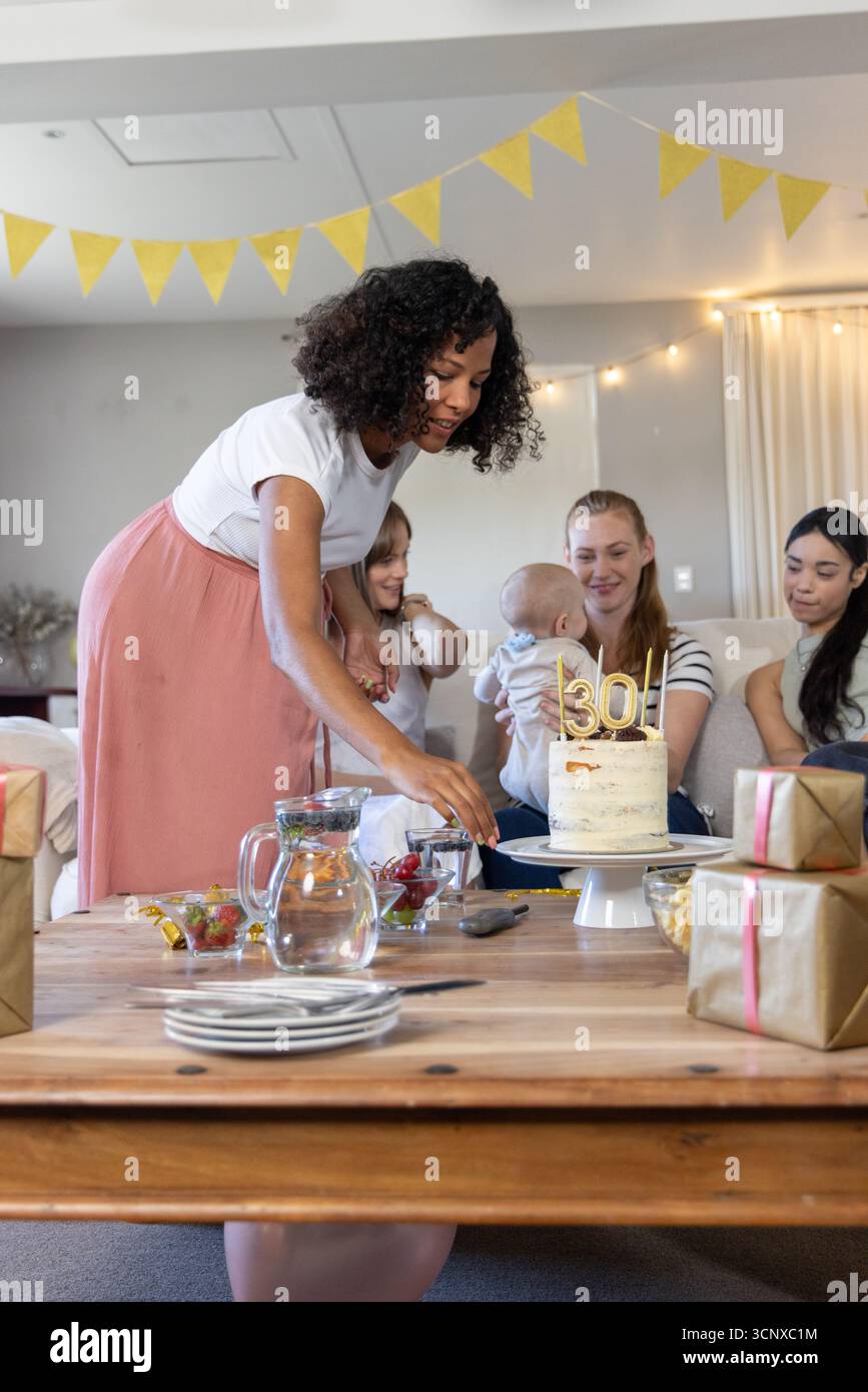 afroamerikanerin schneidet Geburtstagskuchen auf dem Kaffeetisch zu Hause, '30' Kerzen, Kopierraum Stockfoto
