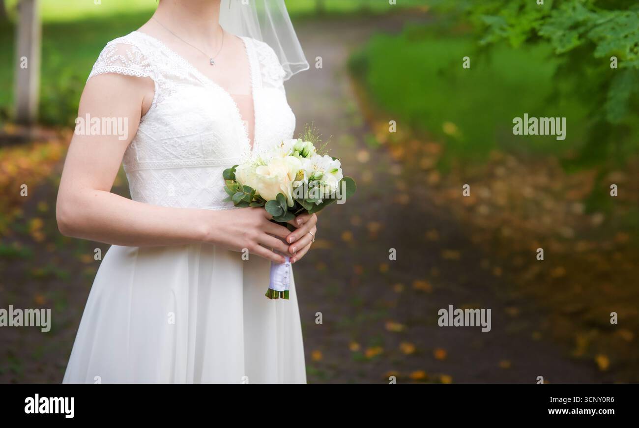 Gerade verheiratete Braut mit wunderschönem Hochzeitskleid in einem grünen Garten, Panorama-Banner mit Kopierraum. Hochzeits- und Liebeskonzept. Stockfoto