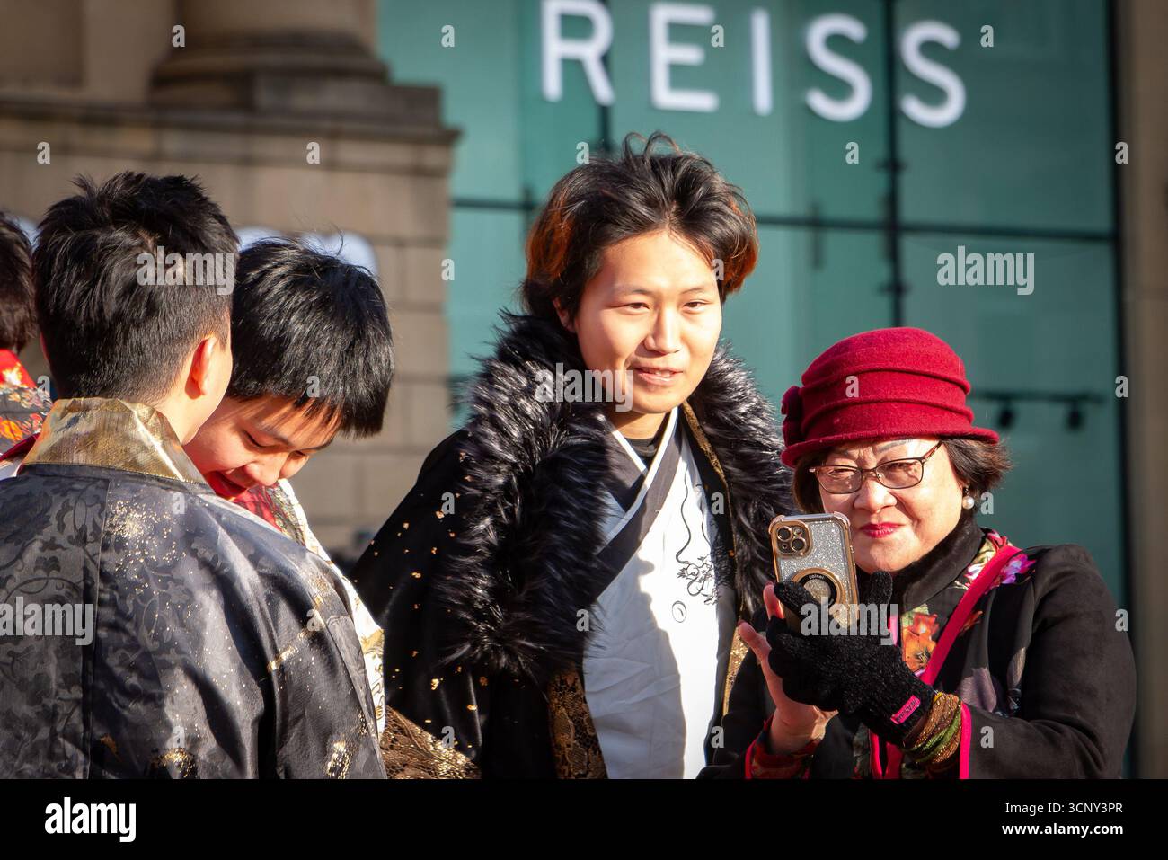 Eine Gruppe asiatischer Menschen in traditioneller Kleidung, die ein Selfie an einem sonnigen Tag in newcastle chinese New Year CNY machen Stockfoto