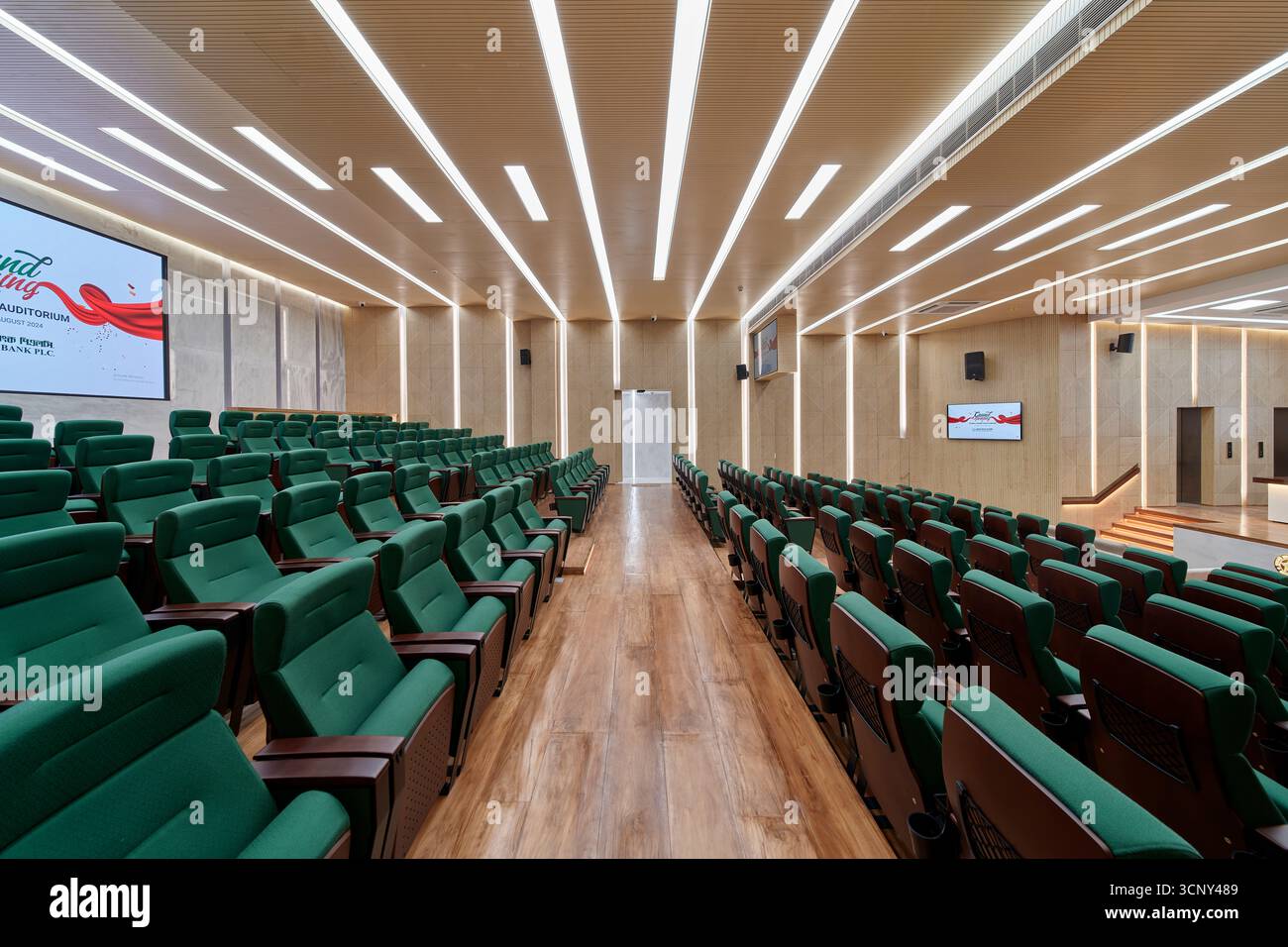 Modernes Auditorium mit grünen Sitzplätzen und markanter linearer Beleuchtung Stockfoto