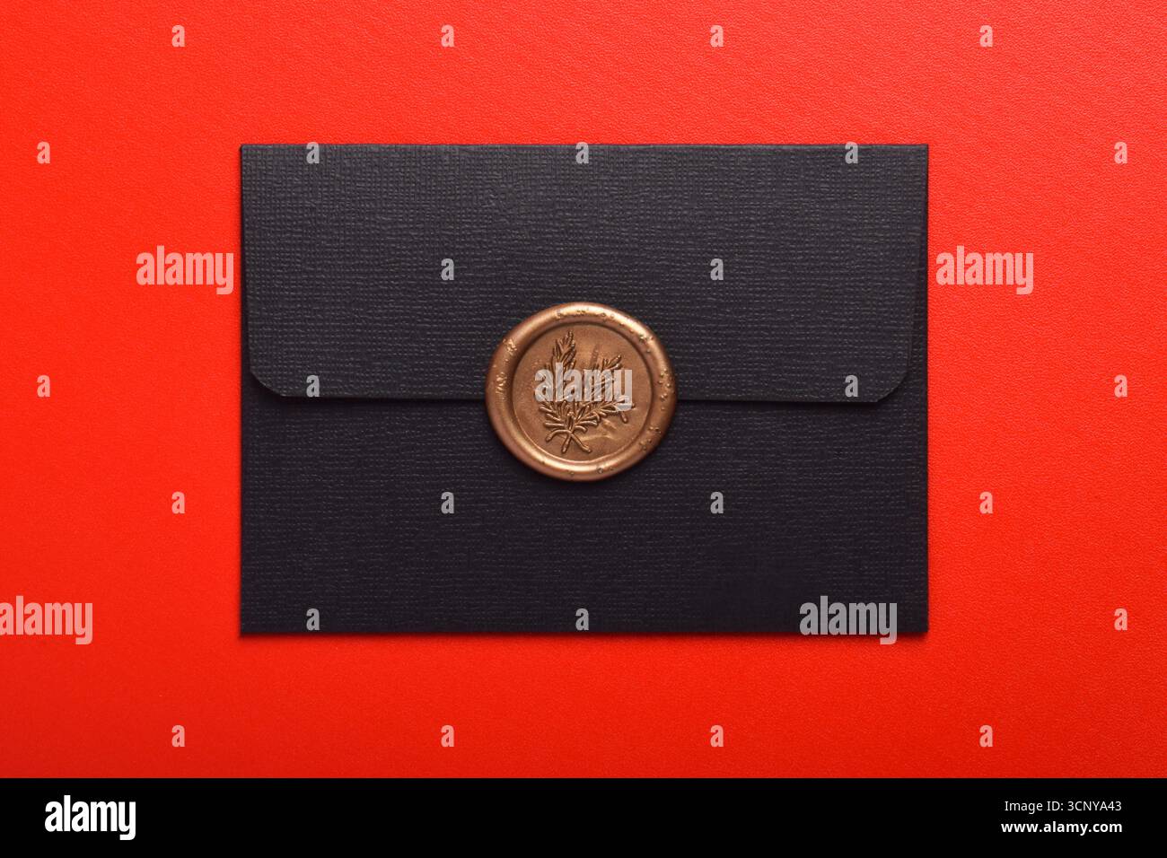 Schwarzer Umschlag mit Wachsversiegelung isoliert auf rotem Hintergrund Stockfoto