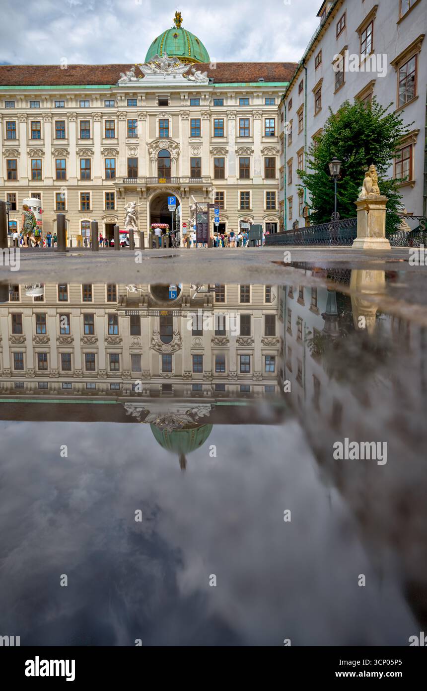 Eine Pfütze im Innenhof der Hofburg spiegelt die barocke Fassade perfekt wider Stockfoto