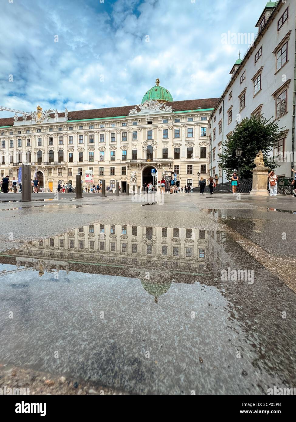 Eine Pfütze im Innenhof der Hofburg spiegelt die barocke Fassade perfekt wider Stockfoto
