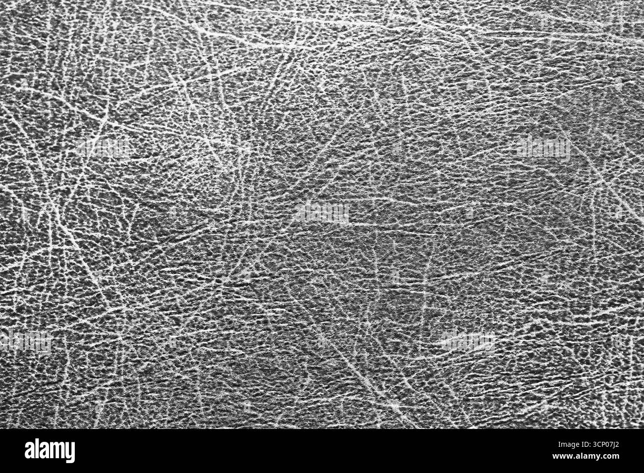 Graue Lederoberfläche mit natürlichen Kratzern und Rissen. Nahaufnahme des Texturhintergrunds. Materialdetails für Design. Abstraktes grobes Muster. Stockfoto