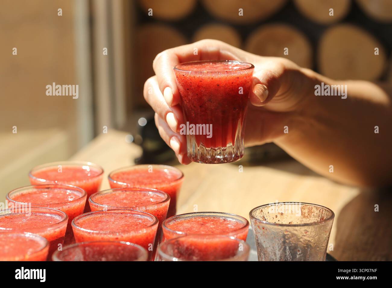 Ein Glas frischer roter Saft in der Hand. Gesunde Frucht Smoothie Nahaufnahme. Erfrischendes Getränk für den Sommer. Natürliches Vitamingetränk. Frisch gepresster Fruchtsaft. Stockfoto