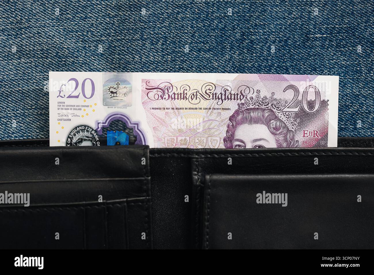 Britische 20-Pfund-Banknote in schwarzer Ledertasche. Nahaufnahme des Geldes in der Tasche. Finanz- und Sparkonzept. Details der Währungsnotiz. Stockfoto