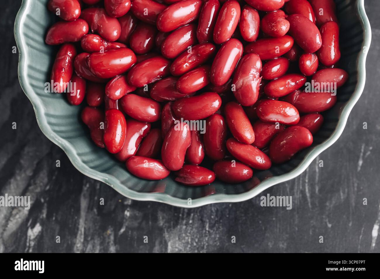 Frische rote Kidneybohnen in grüner Schüssel. Organische Leguminosen-Nahaufnahme. Gesunde vegetarische Eiweißkost. Natürlicher Nährstoffbestandteil. Rohe Bohnen zum Kochen. Stockfoto