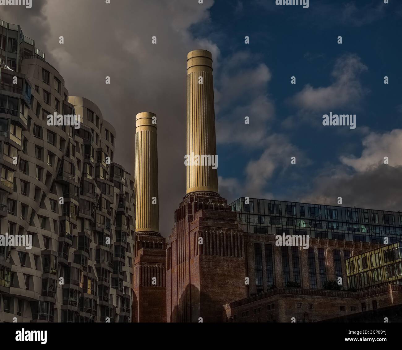 Blick auf das Battersea Power Station in London, Großbritannien, mit zwei berühmten Kaminen, die von warmem Abendlicht beleuchtet werden, umgeben von Wohn- und Bürogebäuden Stockfoto