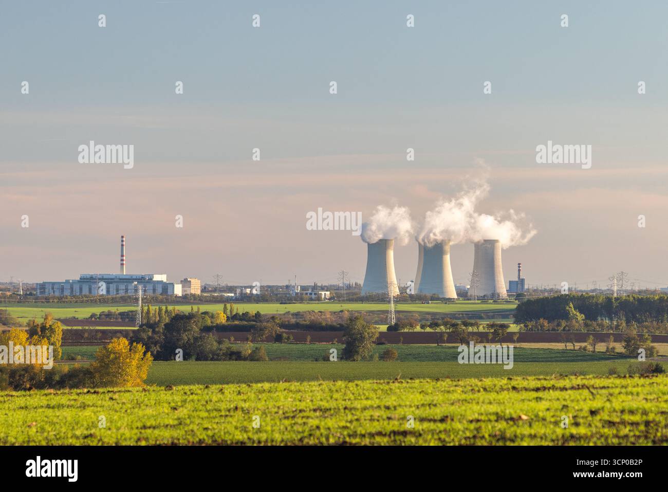 Energielandschaft: Kernkraftwerk inmitten weitläufiger grüner Felder, die zur Stromerzeugung beitragen. Stockfoto
