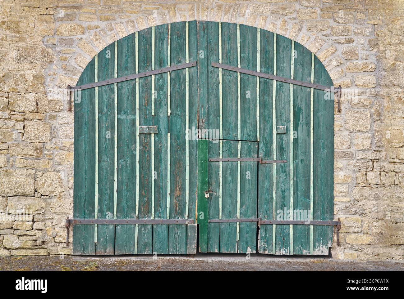 Großes altes grünes Holztor mit integrierter kleiner Tür Stockfoto
