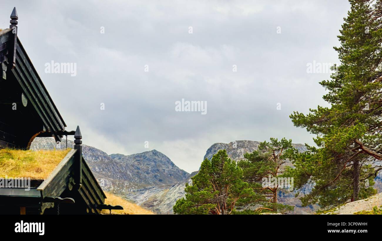 Majestätische Berge erheben sich im Hintergrund, eingerahmt von üppigem Grün und traditioneller Hüttenarchitektur, die die ruhige Schönheit des Herbstes in einer ruhigen Ruhe einfangen Stockfoto