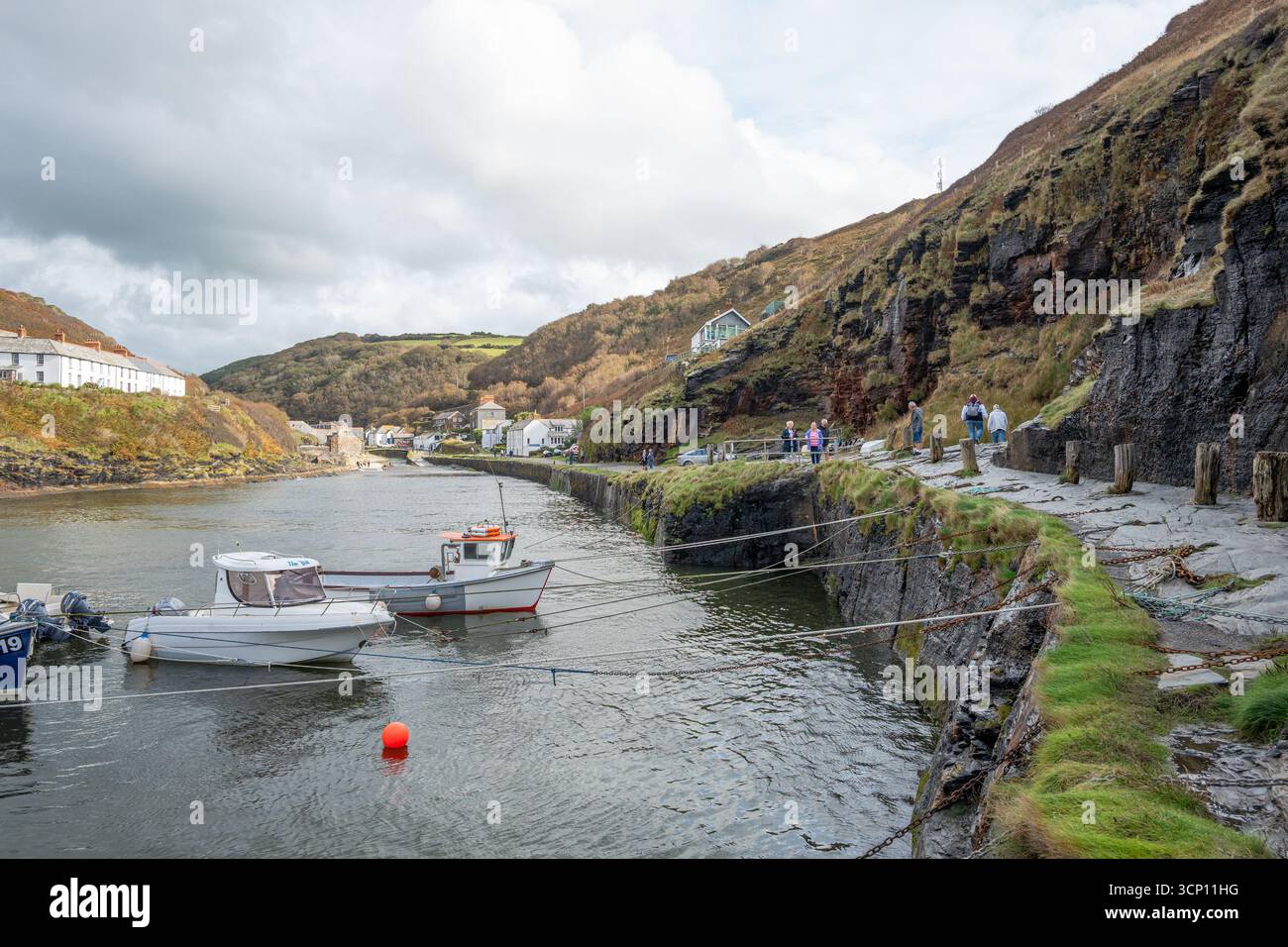 Der natürliche Hafen im kleinen kornischen Fischerdorf Boscastle mit kleinen Fischerbooten und Schiffen, die an der künstlichen Meeresmauer verankert sind. Stockfoto