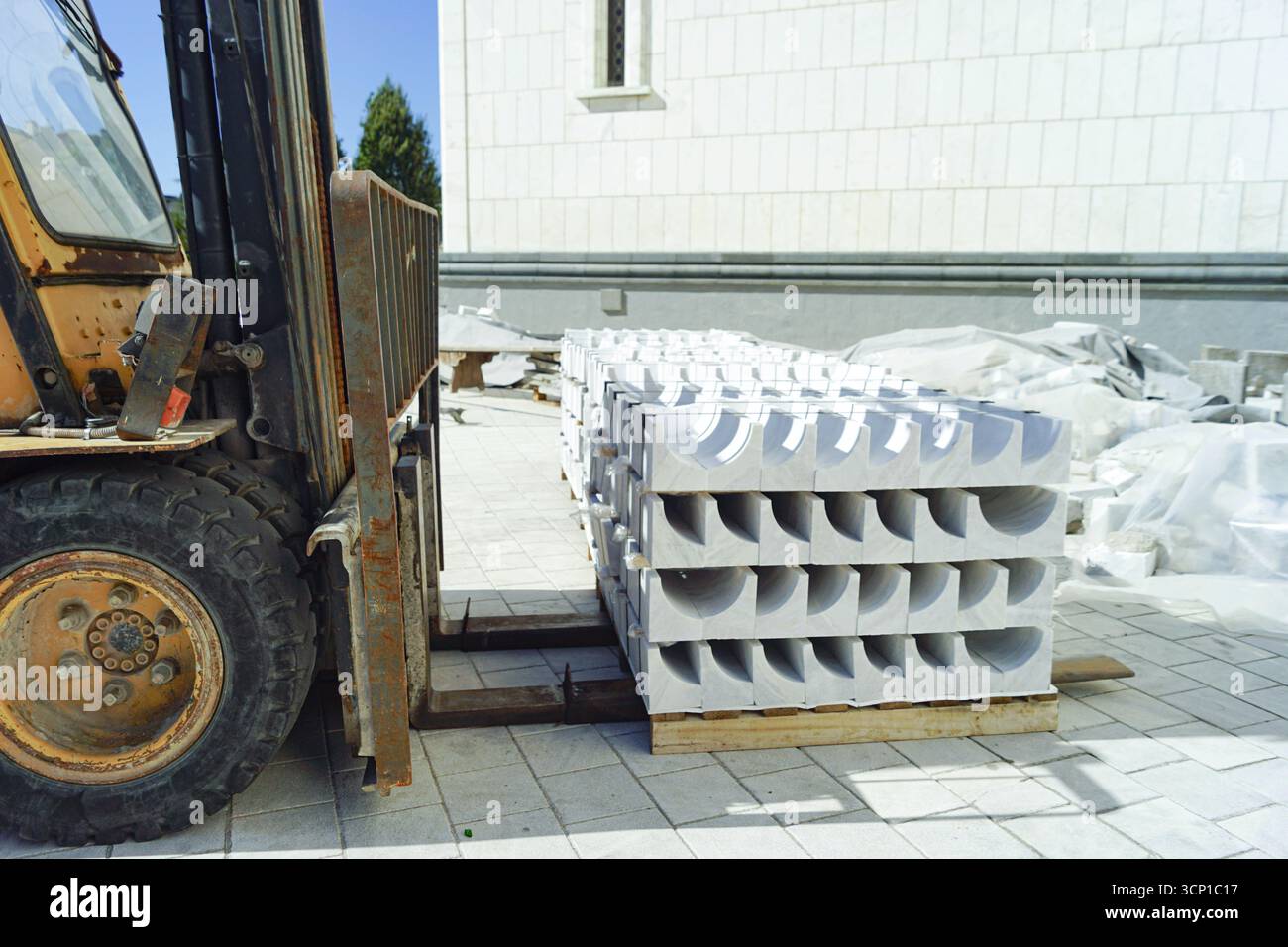 Gabelstapler beladen Steinelemente vor Ort. Baumaschinen und Industriemaschinen. Logistikbetrieb, Stadtentwicklung, automatisierte Prozesse Stockfoto